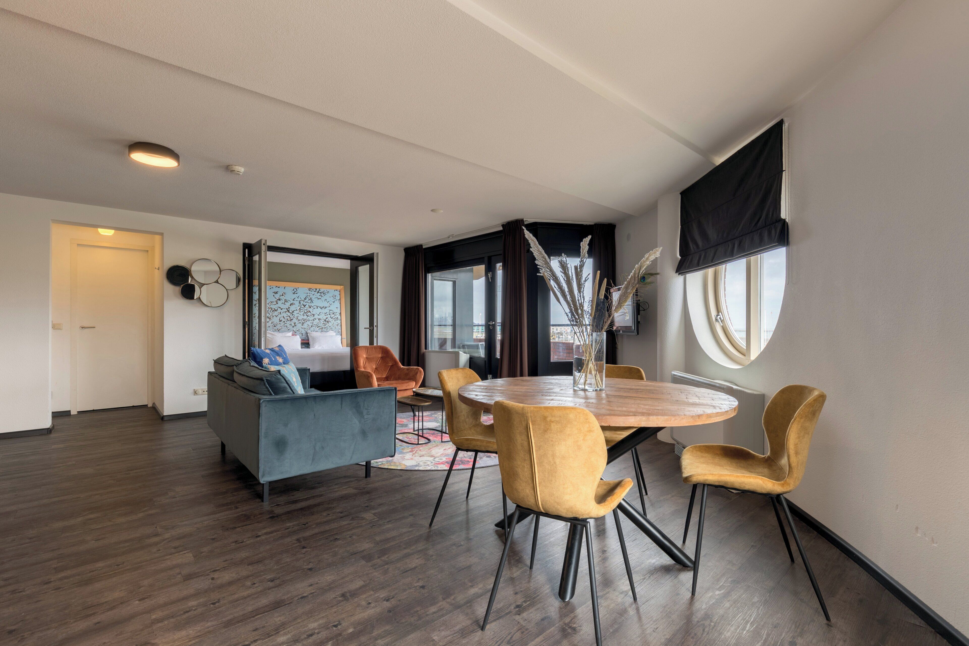 A modern living room with a round wooden dining table, two sofas, and a coffee table.
