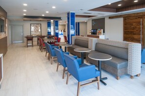 A modern cafe with blue chairs, a grey sofa, and a small round table. - Holiday Inn Express & Suites Plano West - Frisco by IHG (Plano)