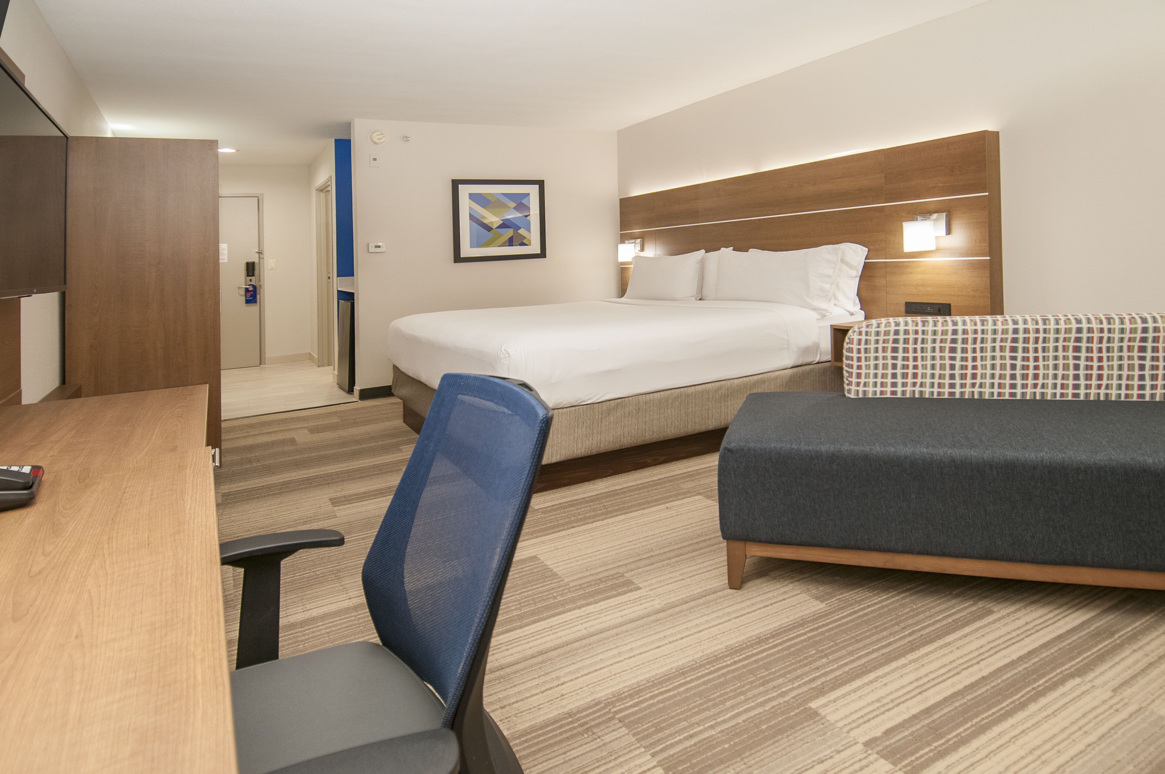 A hotel room with a bed, a desk, a chair, and a sofa.