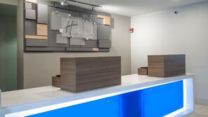 A reception desk with a modern design, featuring a blue illuminated panel and a sign above it. - Holiday Inn Express & Suites Plano West - Frisco by IHG (Plano)