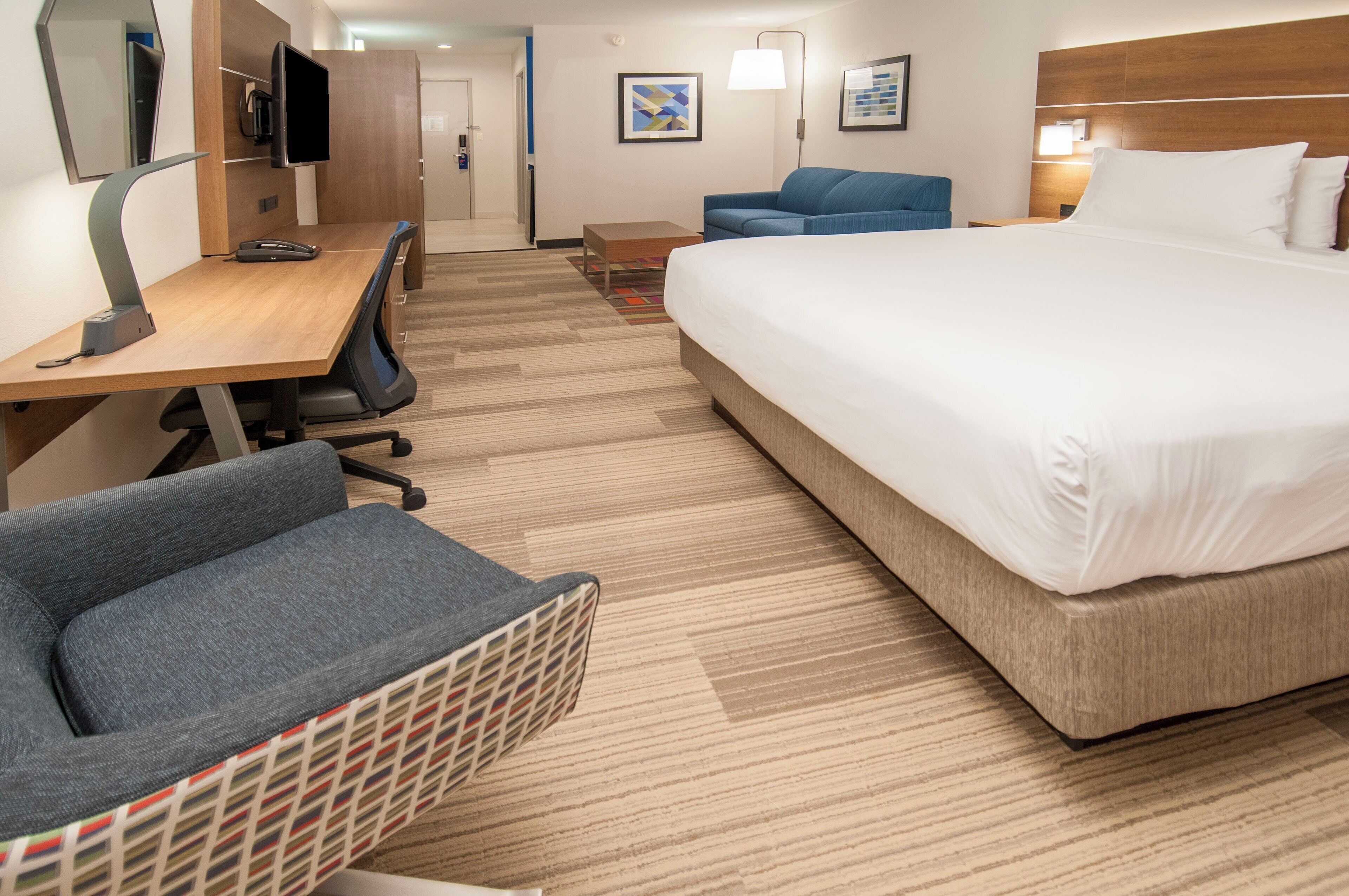 A hotel room with a bed, desk, chair, and a television.