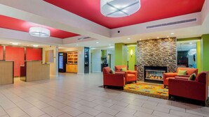 A spacious lobby with a fireplace, red sofas, and a reception desk. - La Quinta Inn & Suites by Wyndham Elkview - Charleston NE (Elkview)