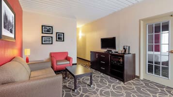 A hotel room with a sofa, a small table, a television, a cabinet, and framed pictures on the wall.