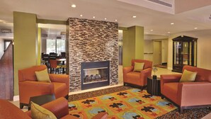 A lobby with orange armchairs, a patterned carpet, and a fireplace. - La Quinta Inn & Suites by Wyndham Elkview - Charleston NE (Elkview)