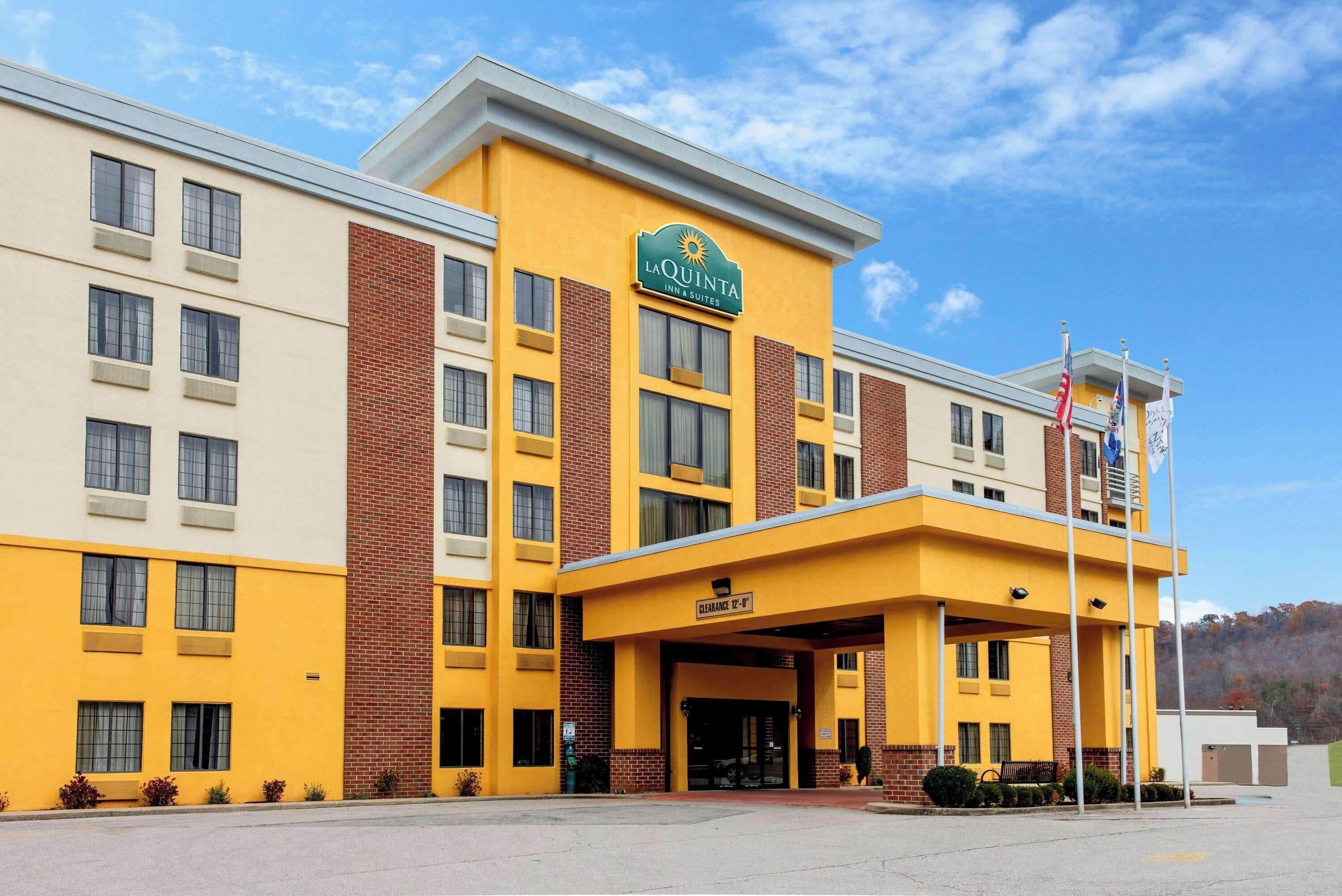 Un bâtiment de la chaîne La Quinta Inn & Suites, avec une façade jaune, de nombreuses fenêtres et un ciel dégagé.