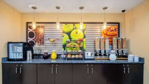 A breakfast bar with a coffee machine, a fruit display, and various food containers. - La Quinta Inn & Suites by Wyndham Elkview - Charleston NE (Elkview)