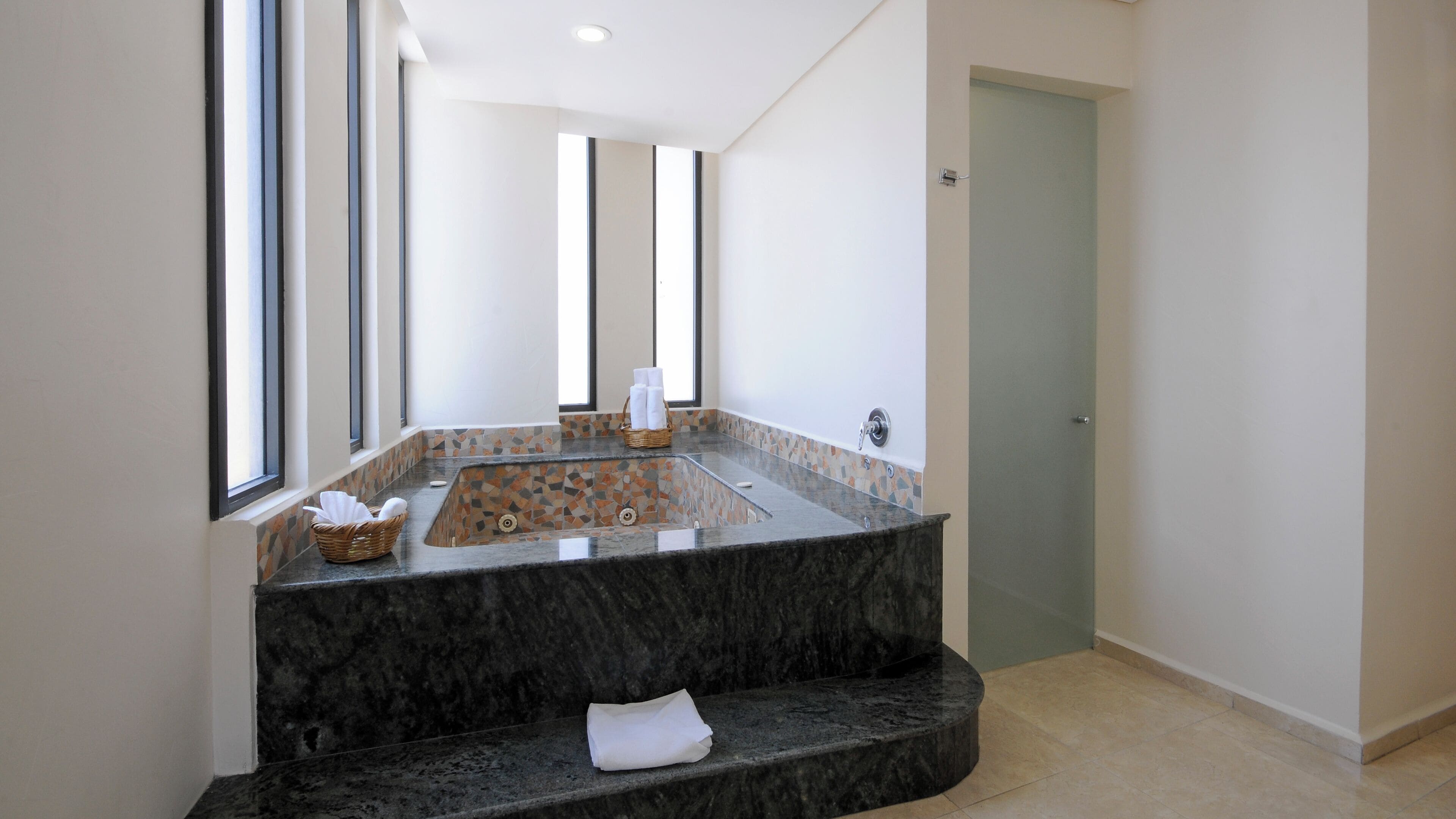 A modern bathroom with a freestanding bathtub, a large mirror, and a tiled backsplash.