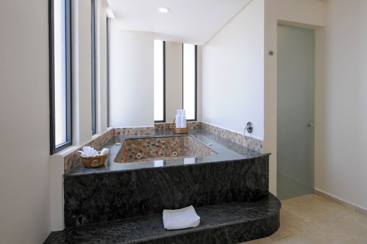A modern bathroom with a freestanding bathtub, a large mirror, and a tiled backsplash.