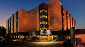 A hotel with a modern architectural design, featuring a prominent entrance with a sign, and a well-lit facade.