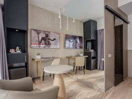 Een moderne hotelkamer met een bank, een ronde tafel, een televisie en een boekenkast.