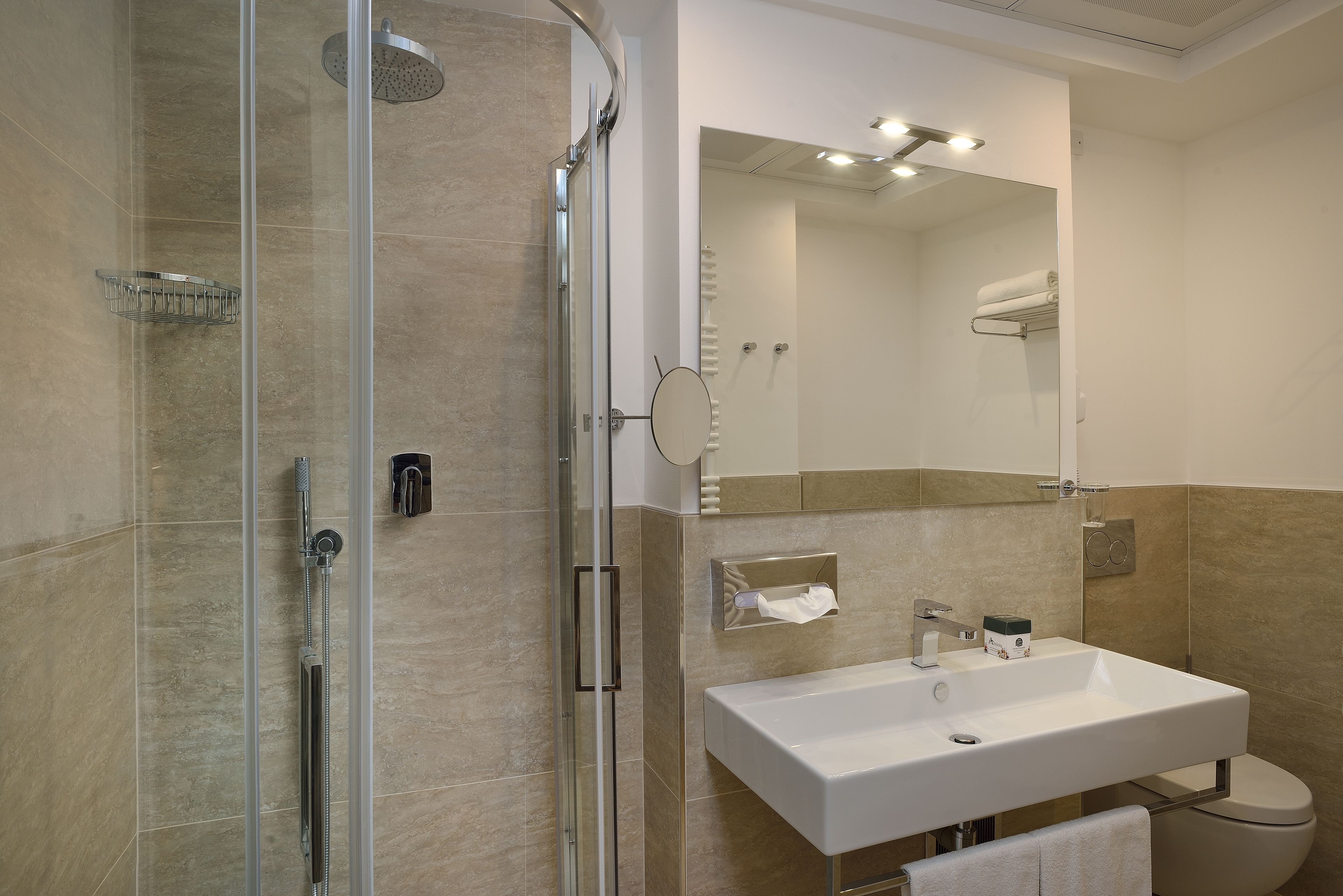 A modern bathroom with a glass-enclosed shower, a white sink, and a mirror above the sink.