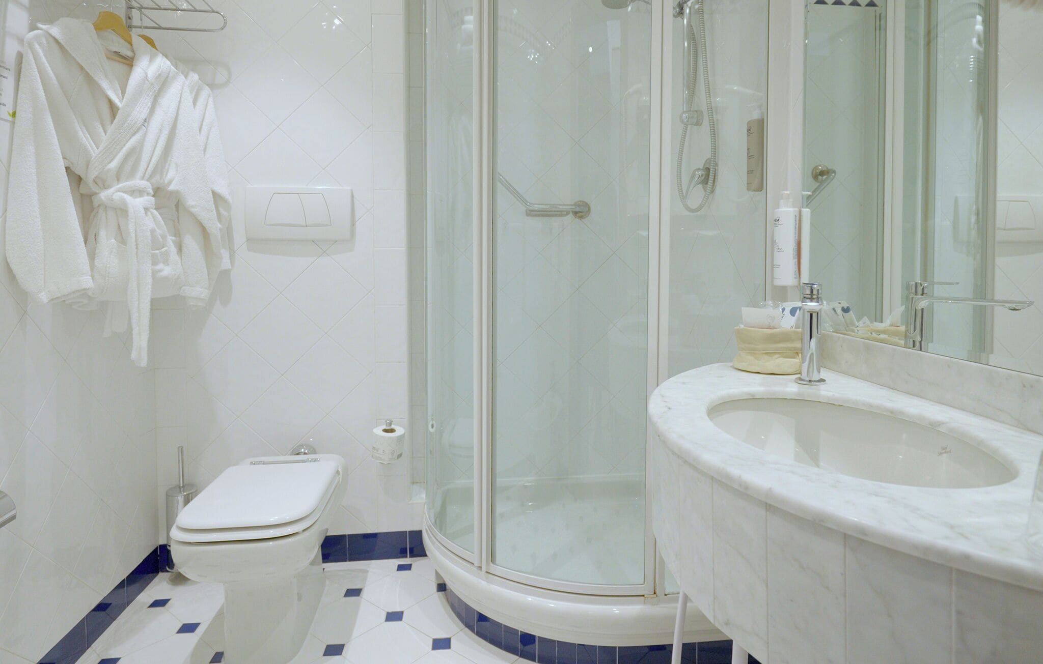 A bathroom with a toilet, a glass-enclosed shower, and a sink with a mirror.