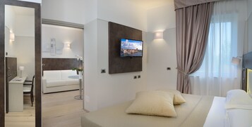 Een moderne hotelkamer met een bed, een televisie, een bureau en een bank.