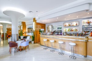 Um bar lounge moderno com balcão, área de estar e diversas bebidas.