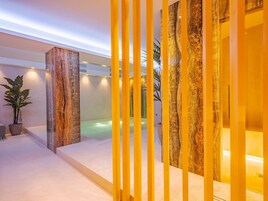 Een moderne spa met een jacuzzi, marmeren zuilen en een potplant.