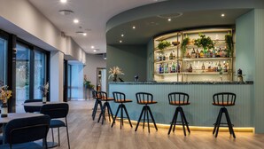 Un área de bar moderna con una barra curva, varios taburetes y una variedad de botellas.