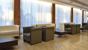 A modern hotel lobby with leather sofas, a coffee table, and a brick accent wall. - Palace Inn (Fiano Romano)