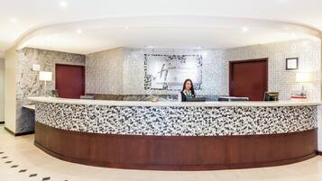 Un mostrador de recepción con diseño de mármol y mosaicos, dos puertas y un letrero que indica Holiday Inn Convention Center.