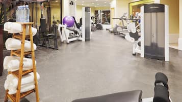 A gym with various exercise equipment, a water dispenser, and a towel rack.