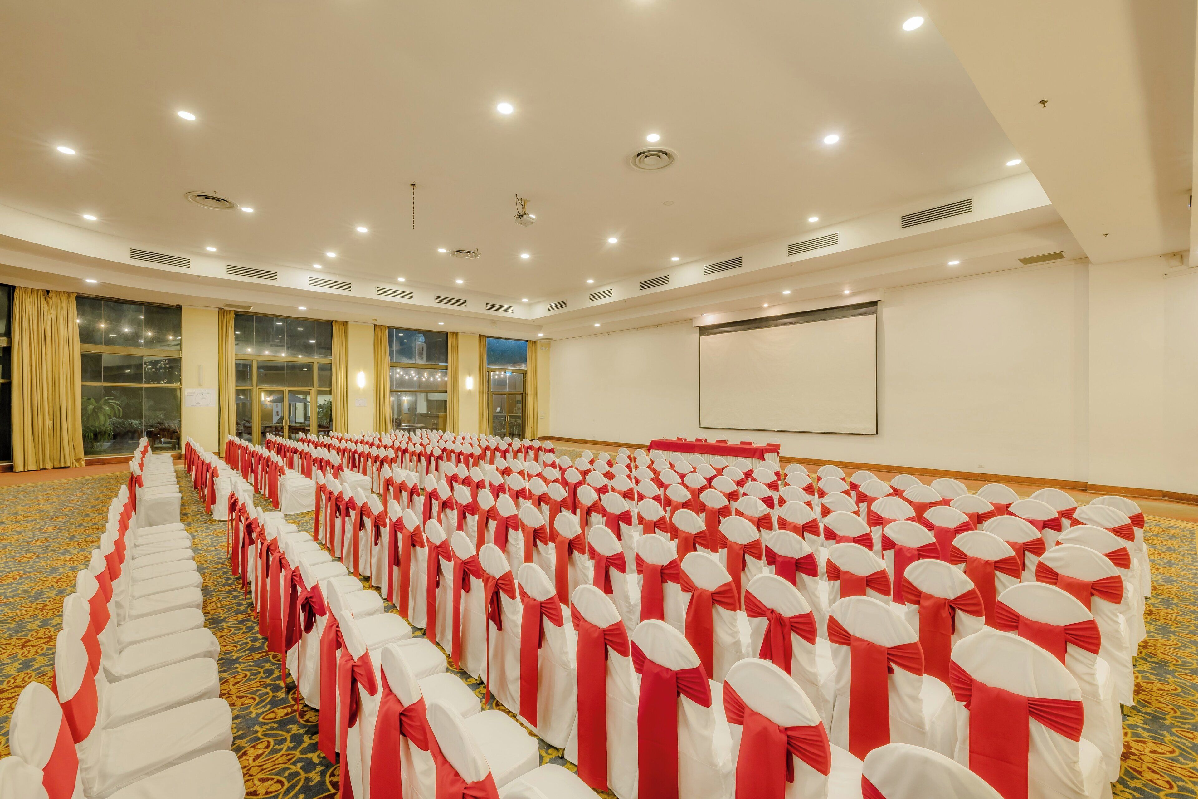 A conference room with rows of chairs, each with a red and white sashed seat cover.
