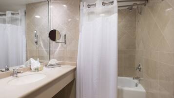 A bathroom with a sink, mirror, and bathtub.