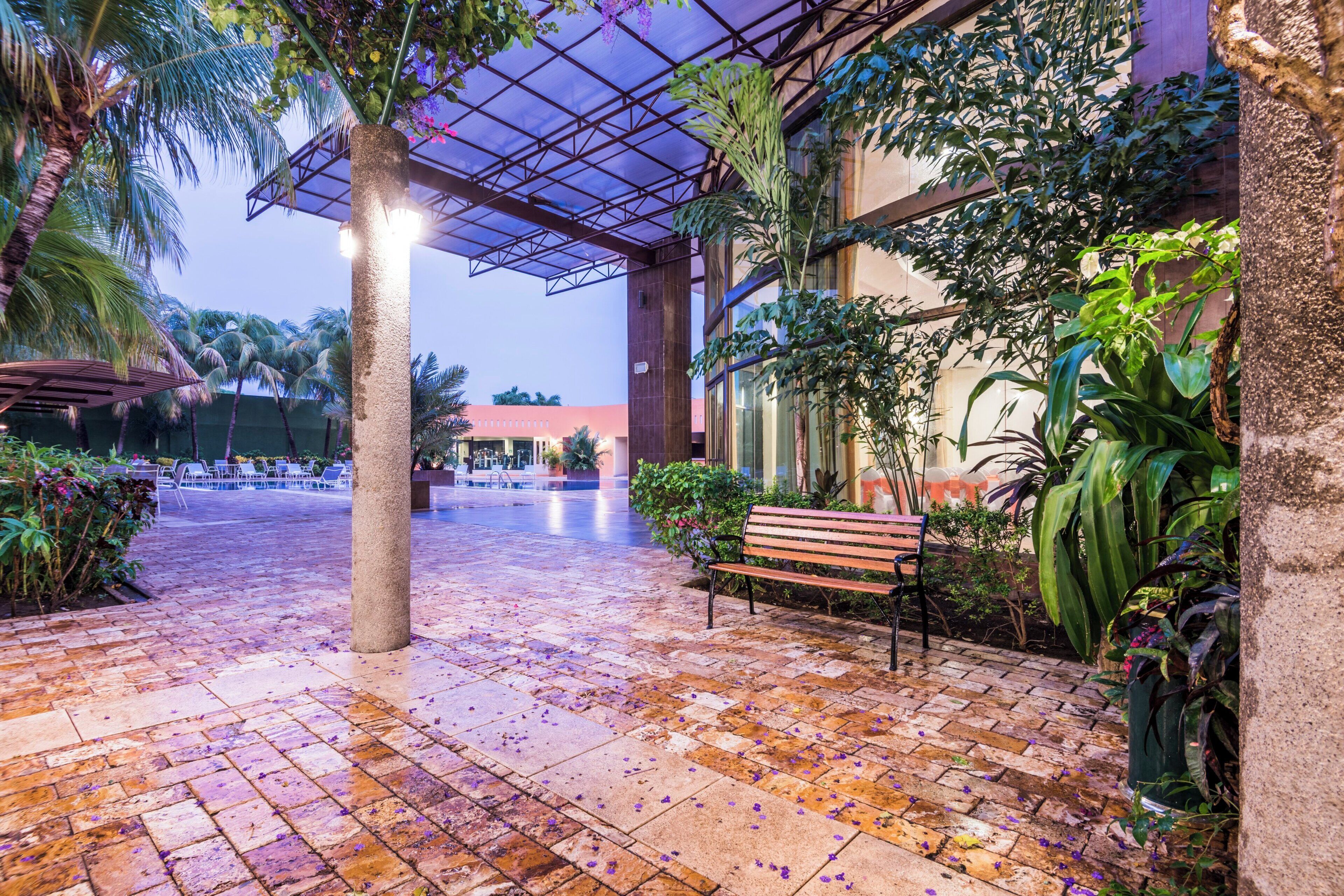 A covered outdoor area with a brick floor, benches, and potted plants.