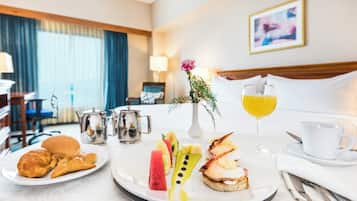 A breakfast setup with croissants, fruit, and a beverage on a tray.