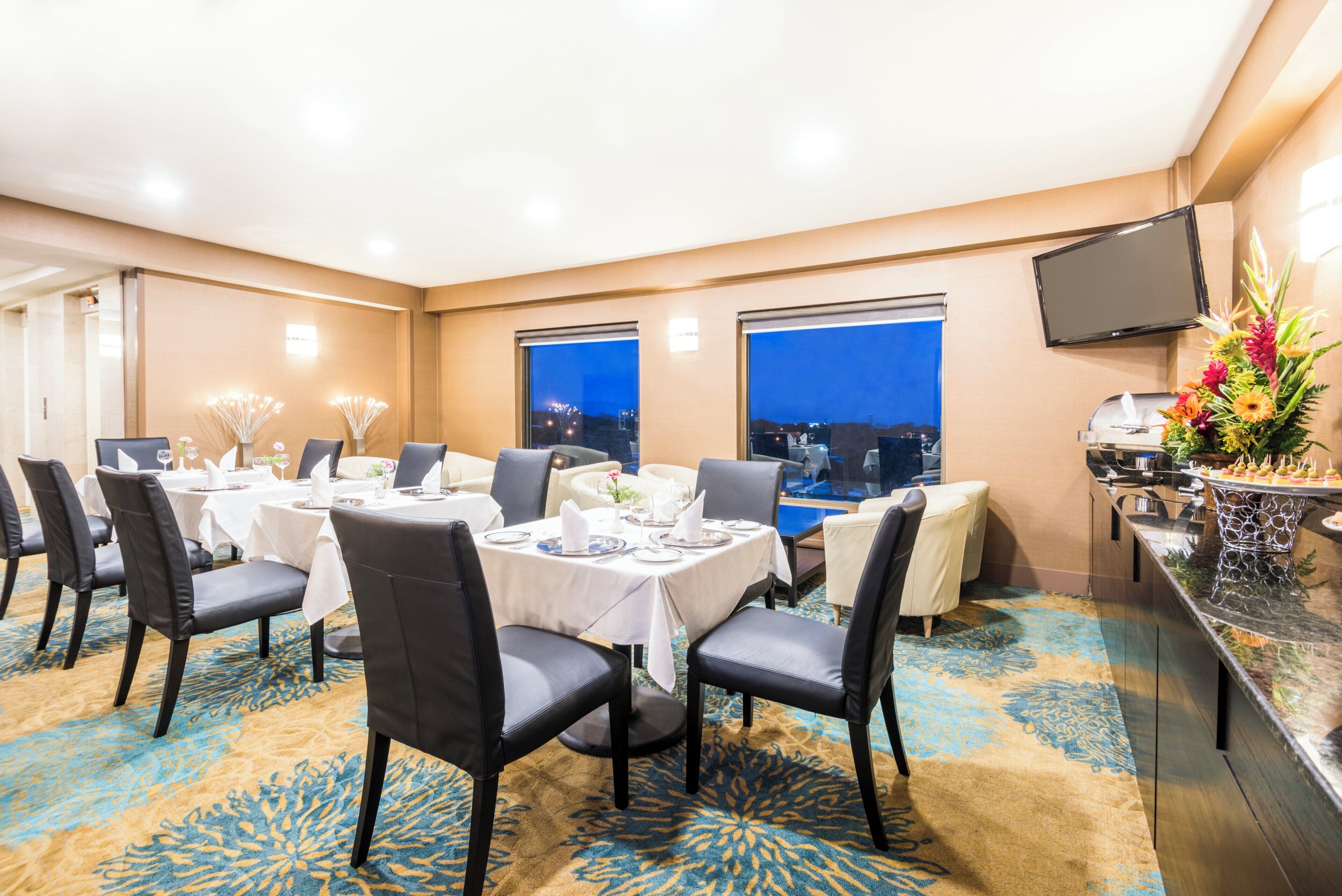 A conference room with a city view, tables set for dining, and a buffet area.