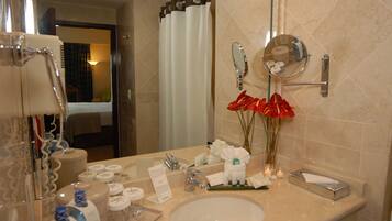 A hotel bathroom with a sink, mirror, toiletries, and a shower curtain.