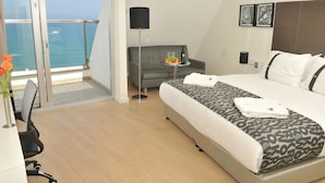 A hotel room with a bed, a sofa, a small table with fruit and wine, a lamp, and a view of the sea. - Harlington Ashkelon (Ashkelon)