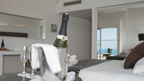 A hotel room with a bed, a bedside table with a champagne bottle, glasses, and a towel. - Harlington Ashkelon (Ashkelon)