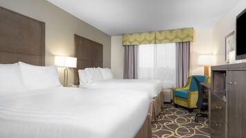 Quarto de hotel com duas camas, uma escrivaninha, uma cadeira, uma televisão e um guarda-roupa.