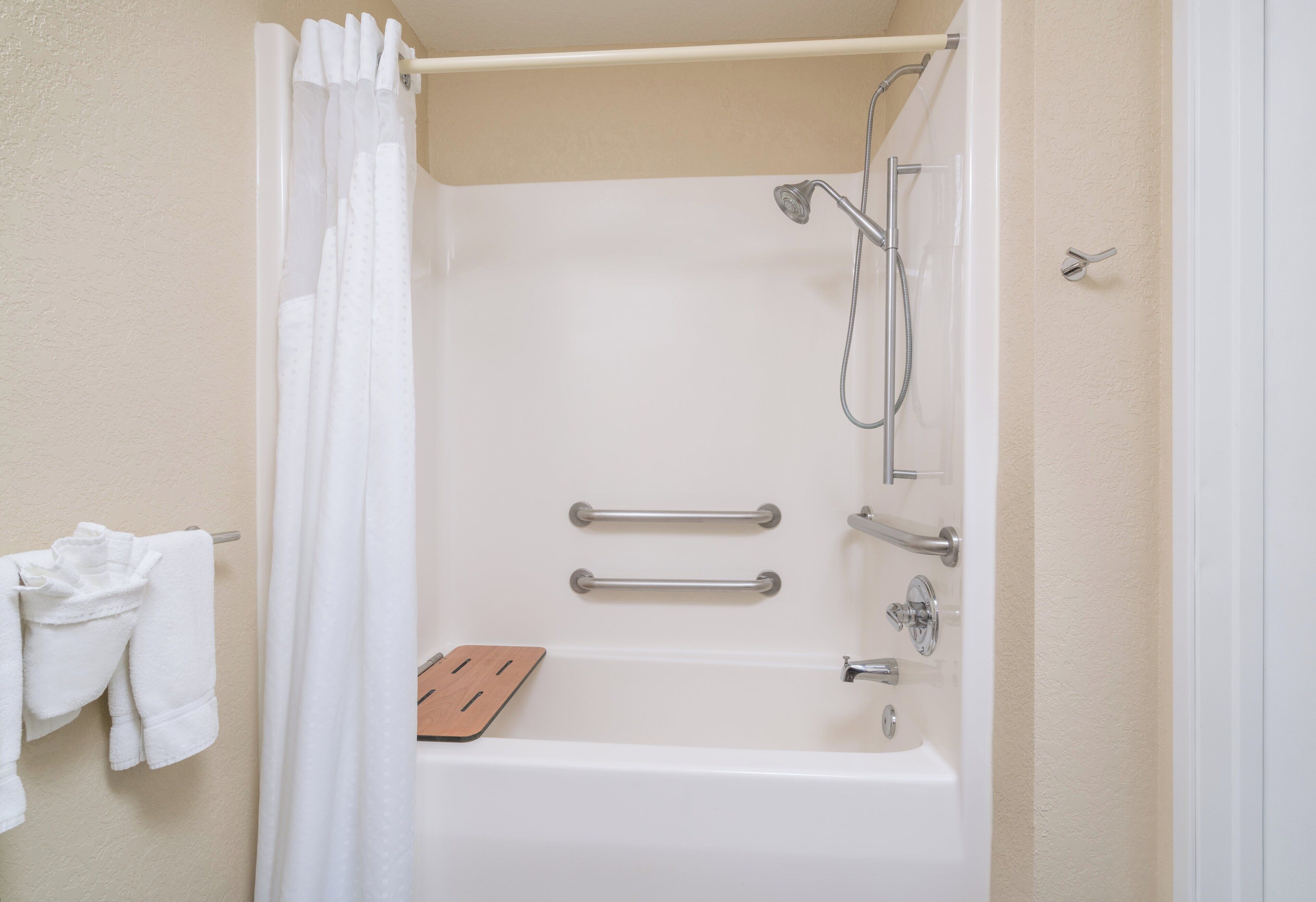 A standard white bathtub with a shower head and grab bars.