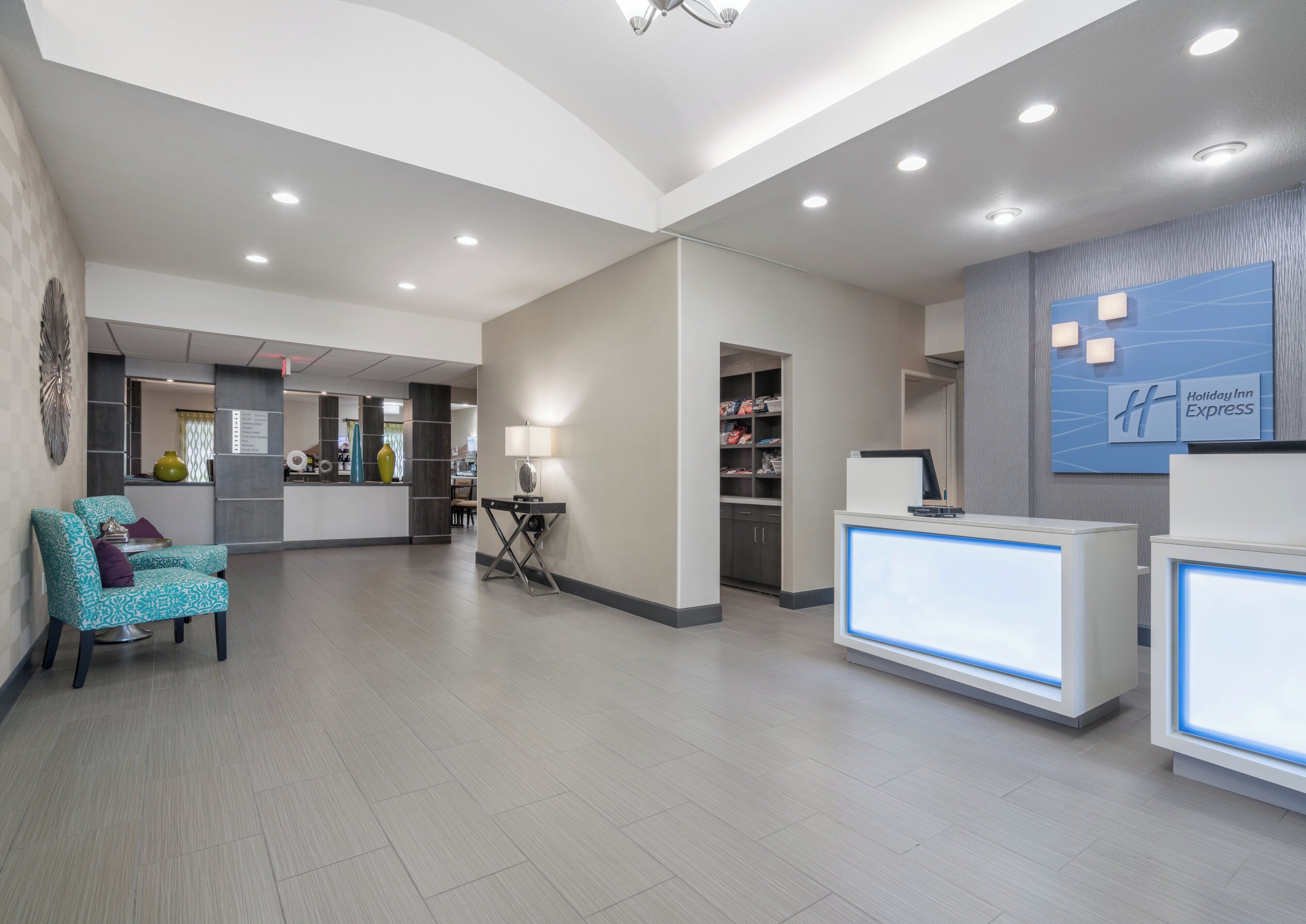 A hotel reception area with a reception desk, a waiting area with a chair, and a wall-mounted sign.