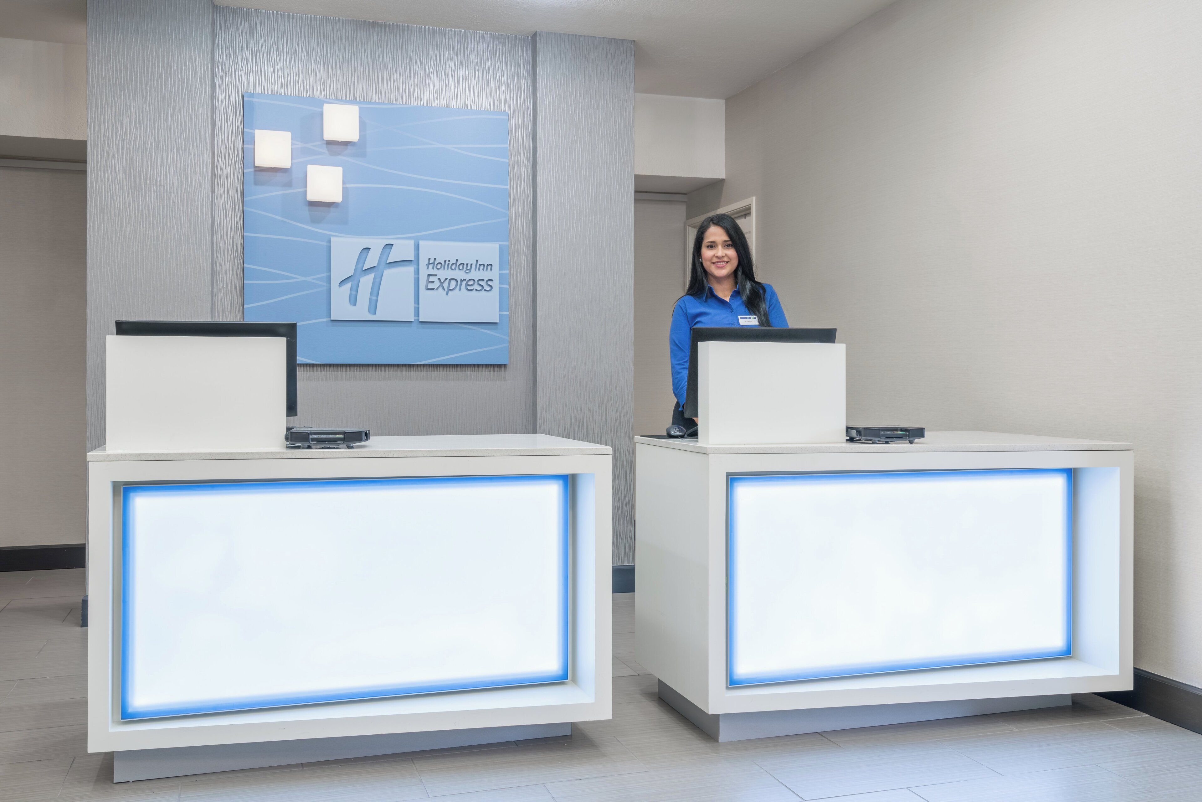 Una recepción con el letrero de Holiday Inn Express, una placa de identificación y una computadora.