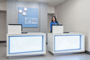 A reception desk with a Holiday Inn Express sign, a nameplate, and a computer. - Holiday Inn Express & Suites Ames by IHG (Ames)