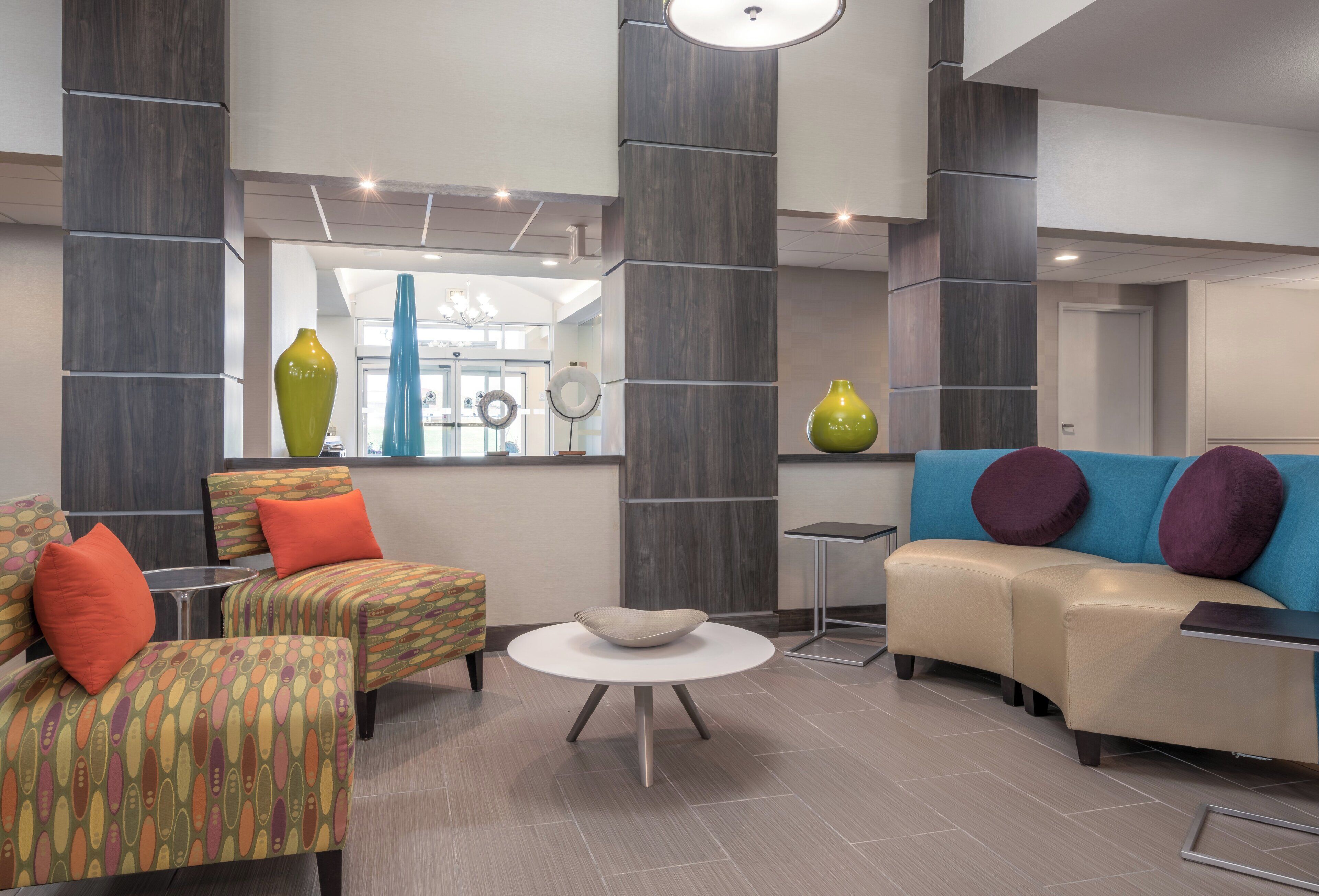 A modern lounge area with a sofa, armchairs, a coffee table, and decorative vases.