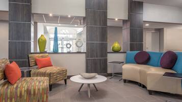 A modern lounge area with a sofa, armchairs, a coffee table, and decorative vases.