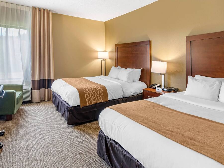 Une chambre d’hôtel avec deux lits, un bureau et une chaise.