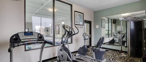 Un gimnasio con cintas de correr, elípticas y una bicicleta estática.