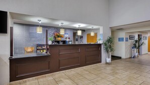 A reception desk with a modern design, a flat-screen TV, and a potted plant. - Best Western Lake Cumberland Inn (Monticello)