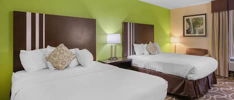 A hotel room with two beds, a nightstand, a lamp, and a framed picture on the wall.