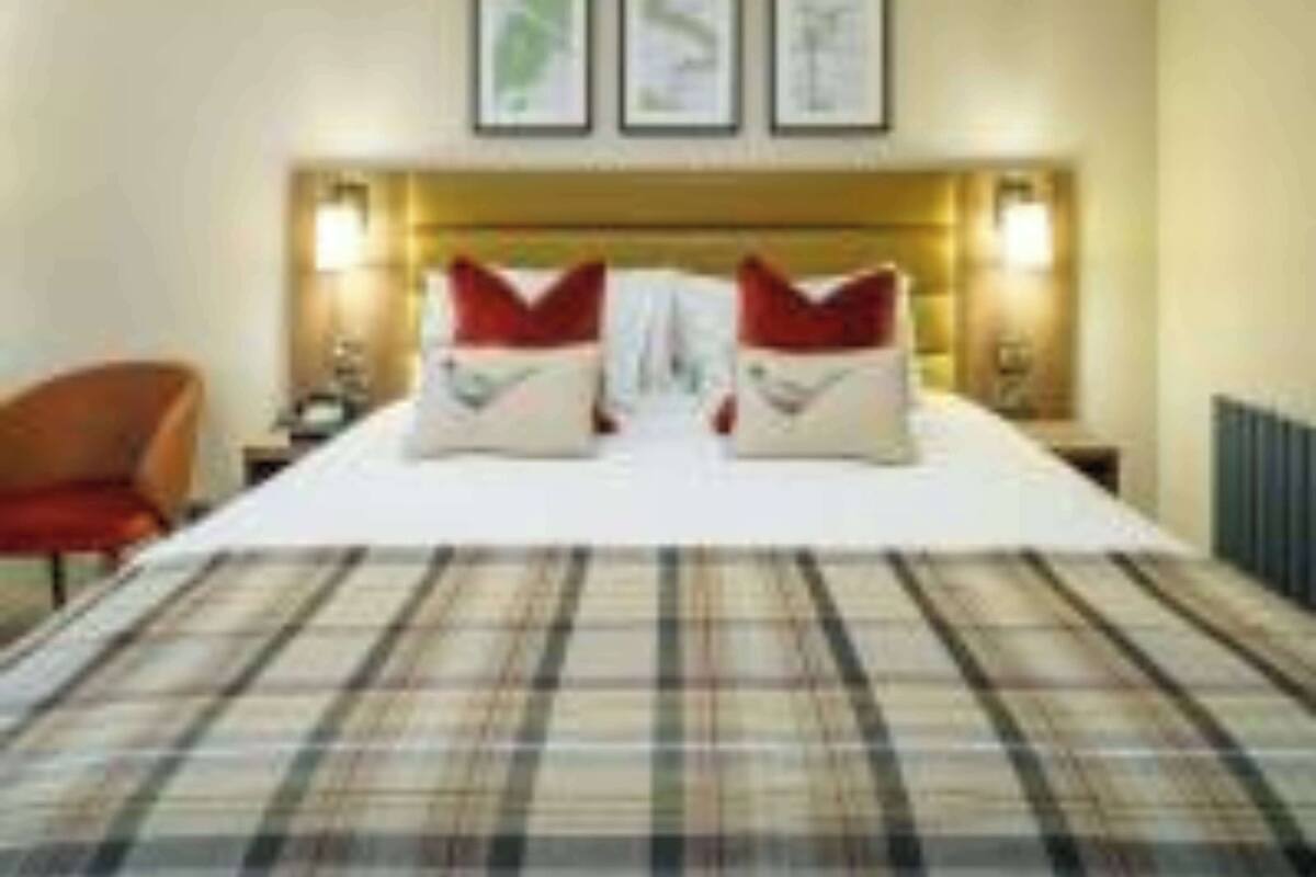 Een hotelkamer met een groot bed, twee nachtkastjes en een stoel.