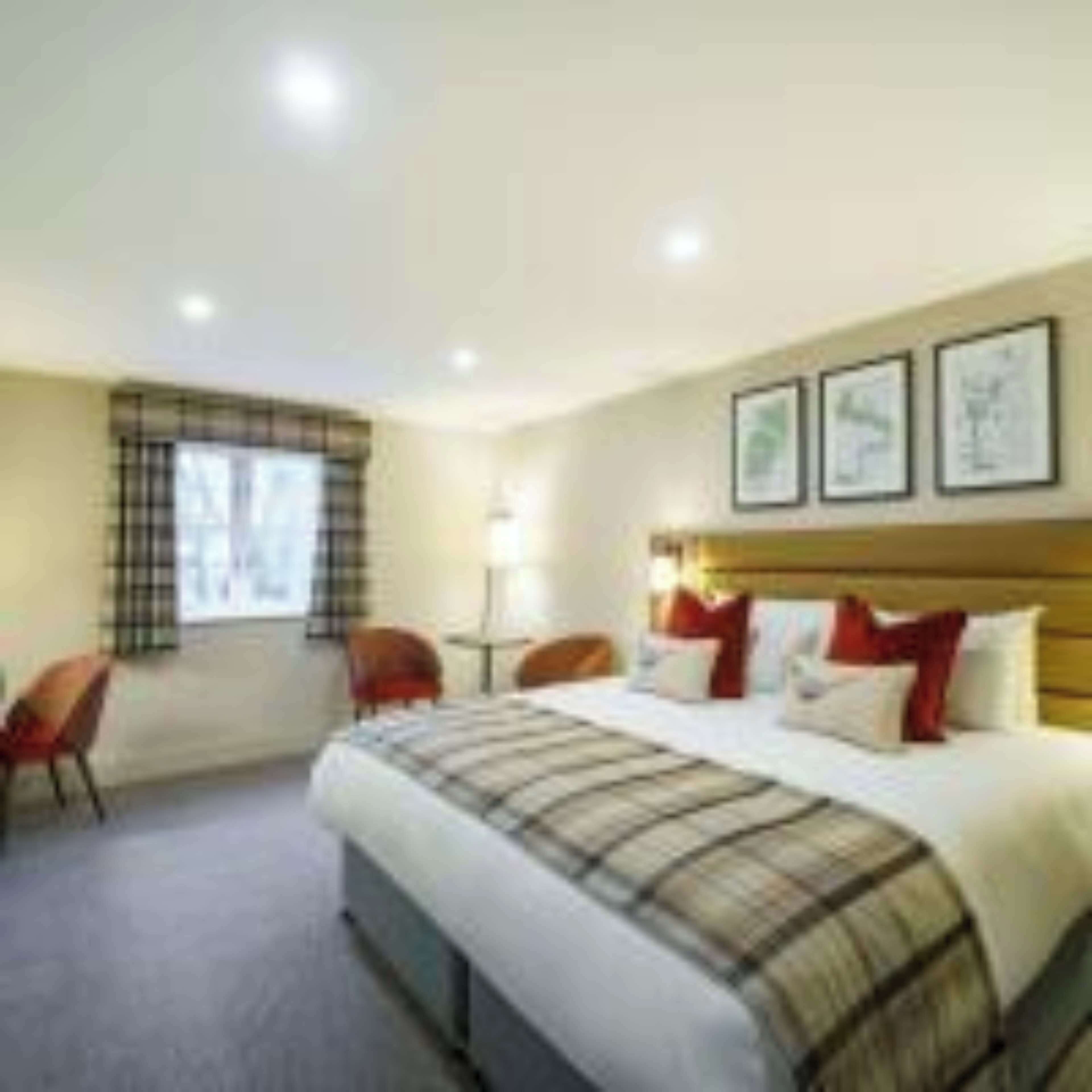 A hotel room with a large bed, a desk, and chairs.