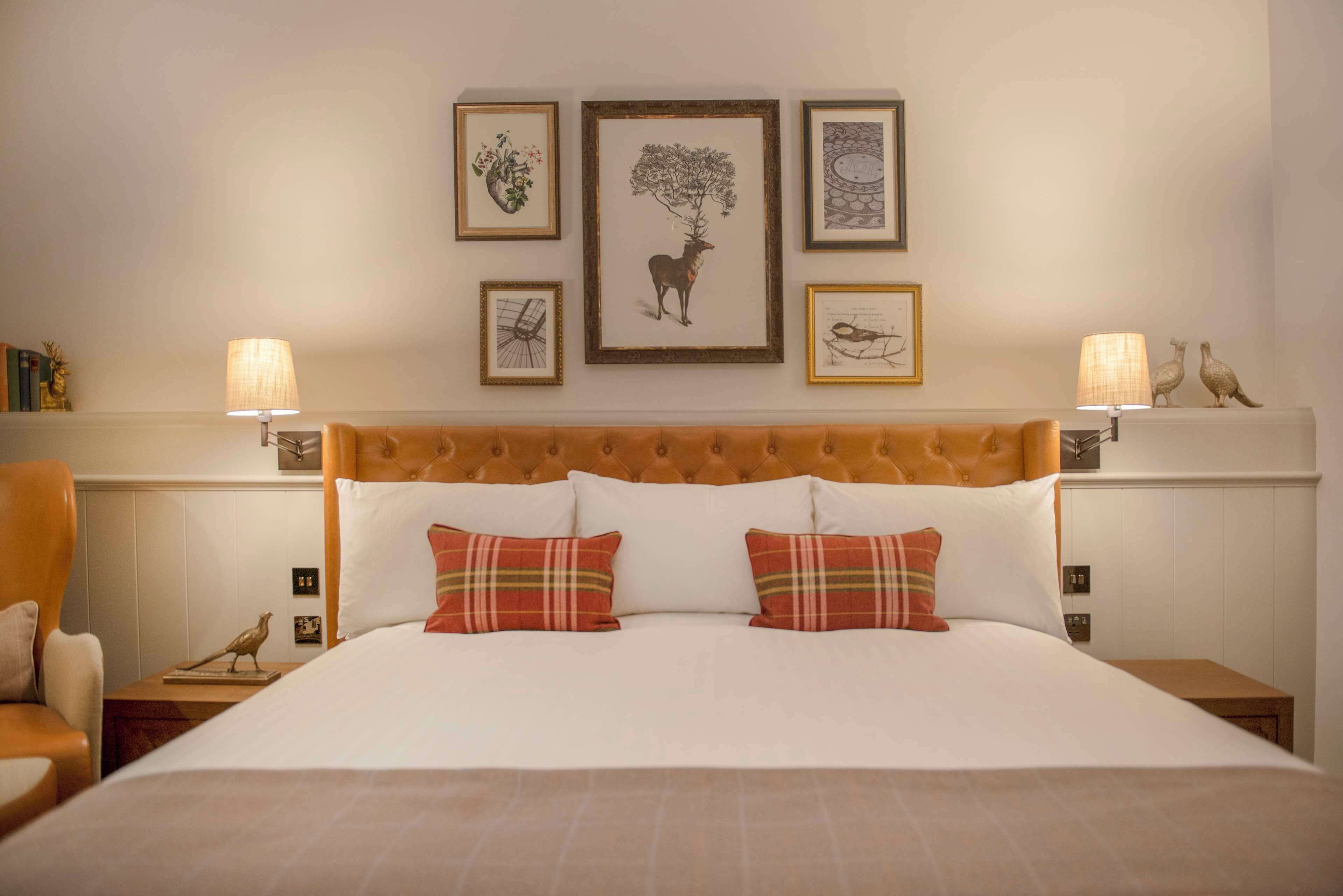 A hotel room with a large bed, two nightstands, a chair, and framed artwork on the wall.