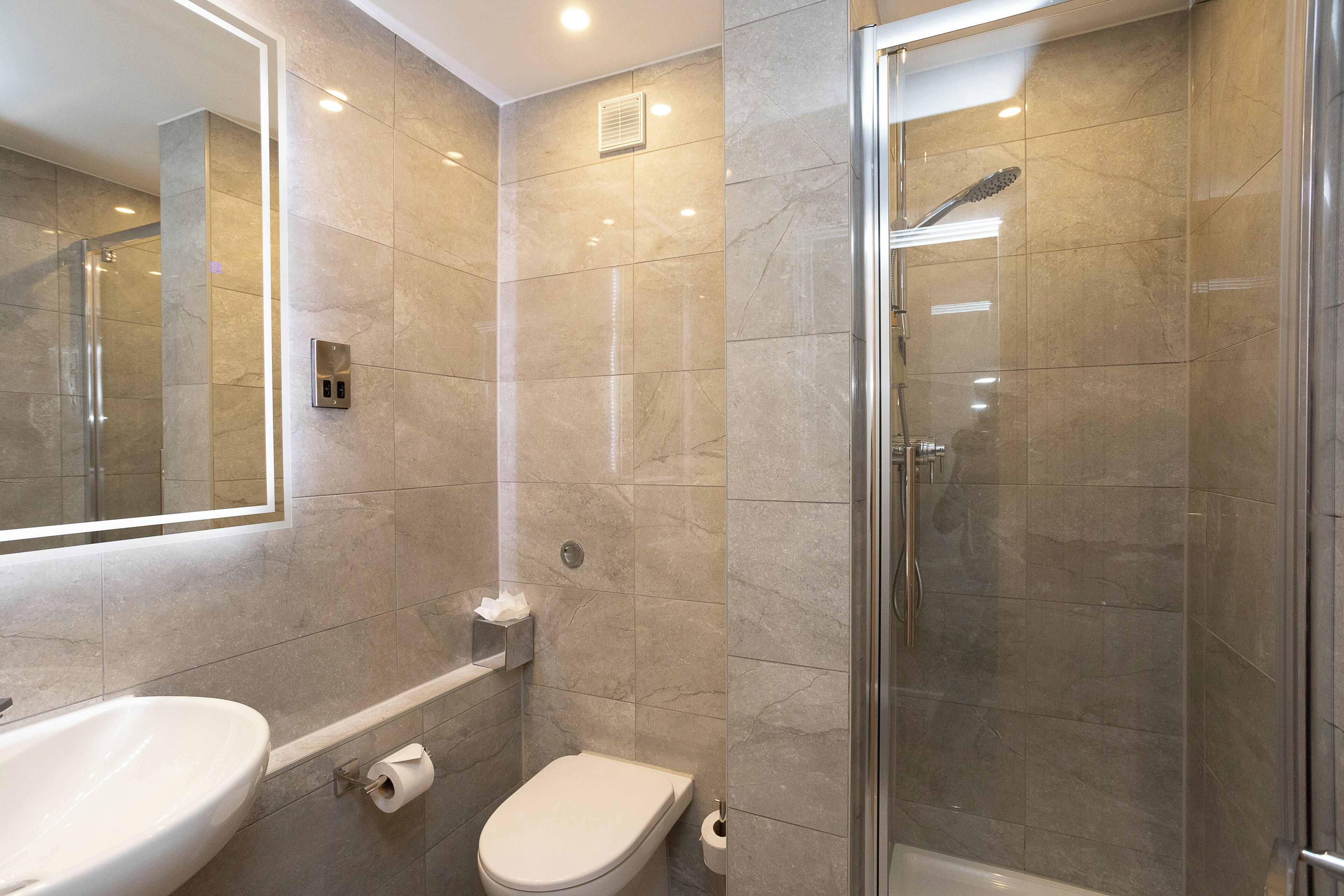 A modern bathroom with a sink, toilet, and glass-enclosed shower area.