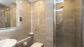 A modern bathroom with a sink, toilet, and glass-enclosed shower area.