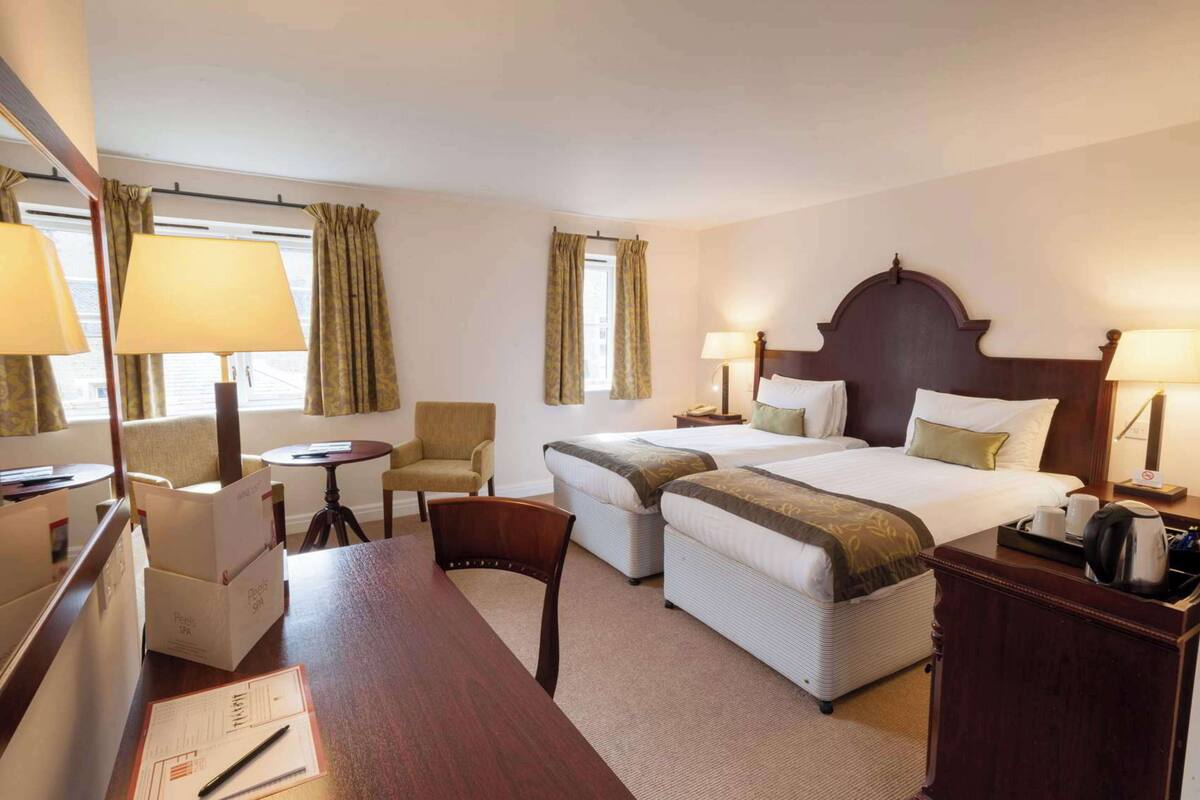 Een hotelkamer met twee bedden, een bureau, een stoel en een tafel.