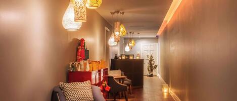 A hallway with modern pendant lighting, a reception desk, and a seating area with a small table and chairs.