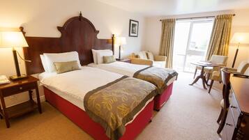 A hotel room with two beds, a desk, a chair, and a small table.